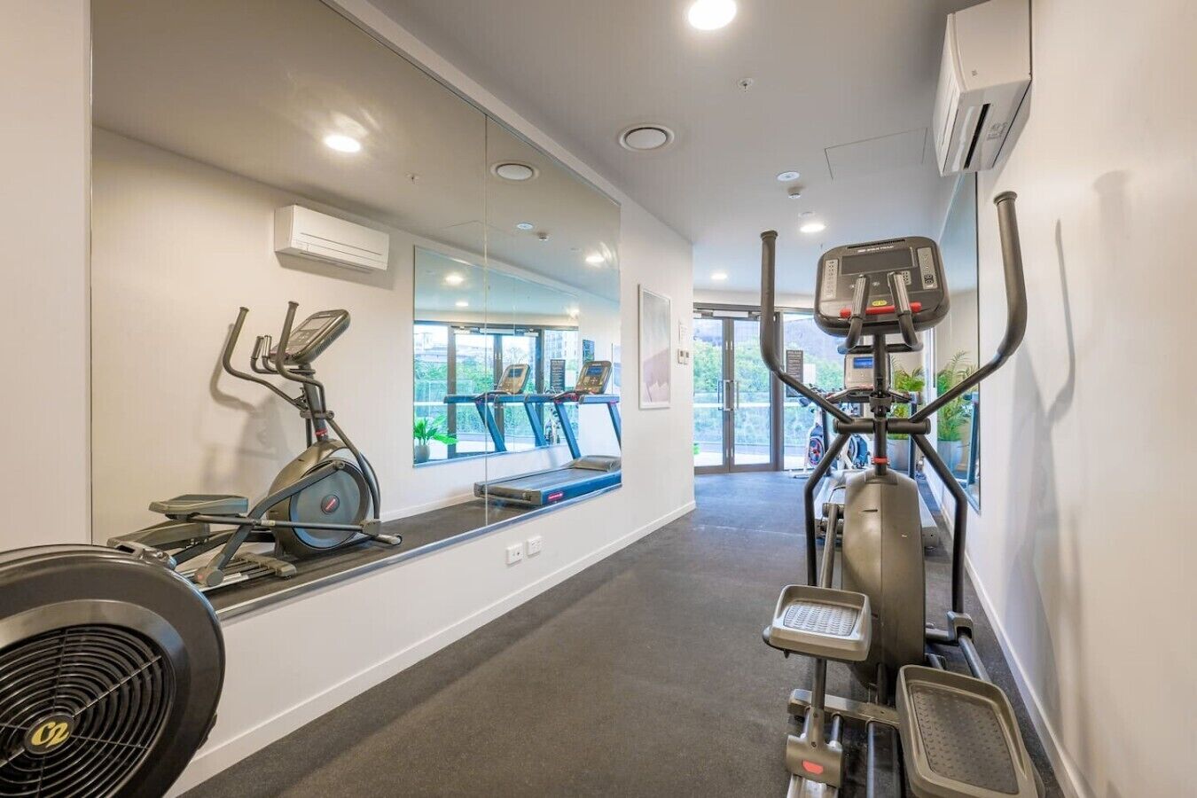 Une salle de sport équipée de matériel d’exercice, dotée d’un grand miroir et d’une fenêtre donnant sur l’extérieur.