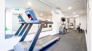 Une salle de sport équipée d’un tapis de course, d’un vélo d’exercice et de divers appareils de musculation.