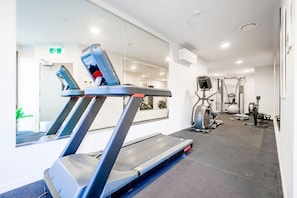 Un gimnasio con cinta de correr, bicicleta estática y diversos equipos de ejercicio.