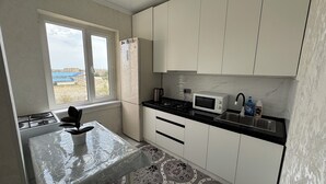 A kitchen with white cabinets, a gas stove, a microwave, and a sink. - Charming 2-bedroom apartment in delightful Balykchy with WiFi (Balykchy)