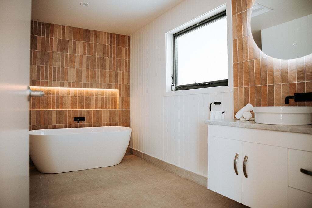 Un baño moderno con una bañera independiente, una ventana y un tocador con espejo.