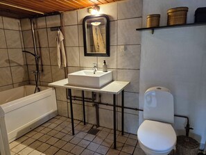 Une salle de bain Ă©quipĂ©e dâune baignoire, dâun lavabo, de toilettes et dâune douche.