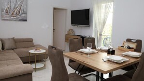 Un soggiorno moderno con un divano, un tavolo da pranzo per quattro persone e un televisore montato a parete.