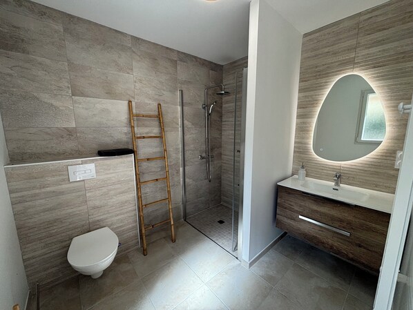 Un baño moderno con ducha, inodoro y tocador.