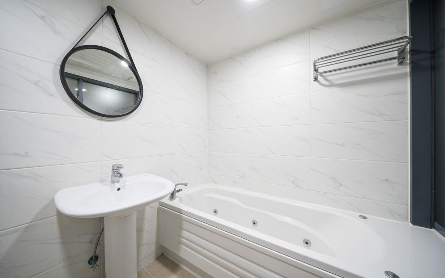 A bathroom with a white sink, a bathtub, and a mirror.