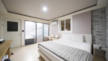 Un dormitorio moderno con una cama grande, un escritorio, una silla y una mesita.
