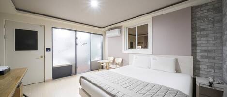 A modern bedroom with a large bed, a desk, a chair, and a small table.