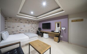 A modern room with a brick-patterned wall, a white sofa, a wooden desk, a computer, and a television. - Daegu Suseong DRAMA (Daegu)