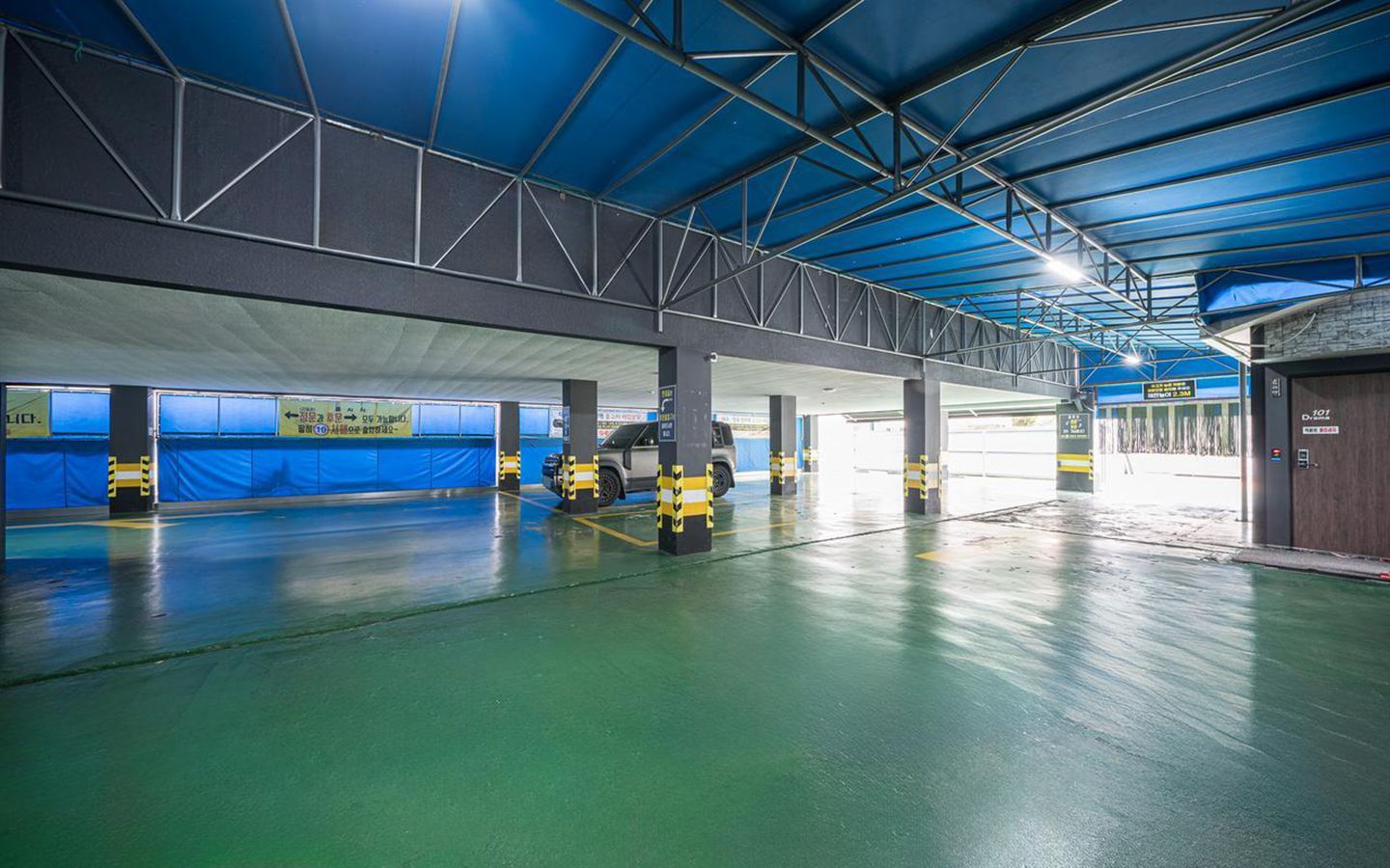 Garagem de estacionamento coberta com vários níveis, vagas demarcadas e teto azul.
