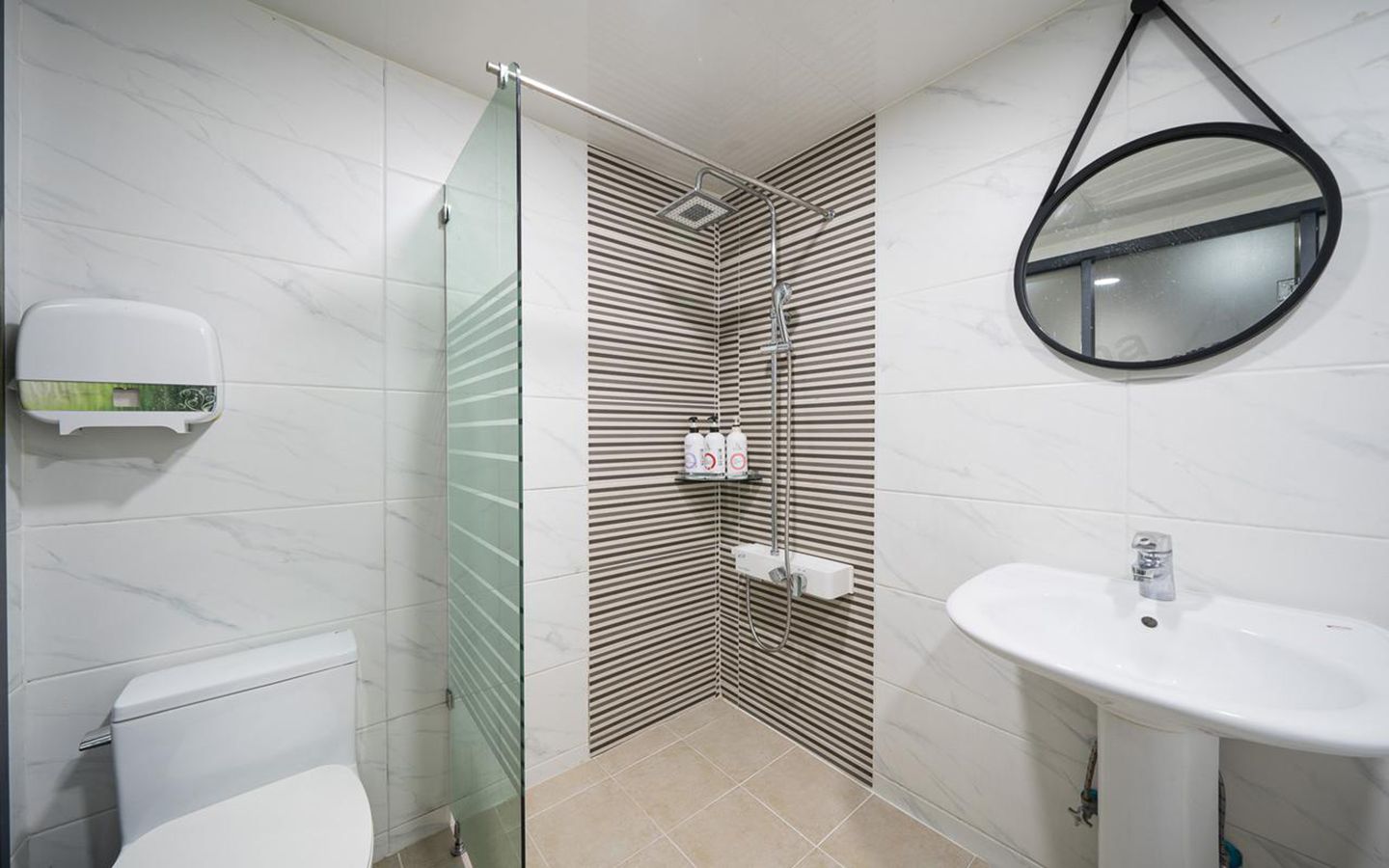 Un baño moderno con cabina de ducha de vidrio, inodoro, lavabo y espejo.