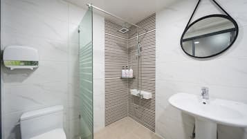 Un baño moderno con cabina de ducha de vidrio, inodoro, lavabo y espejo.