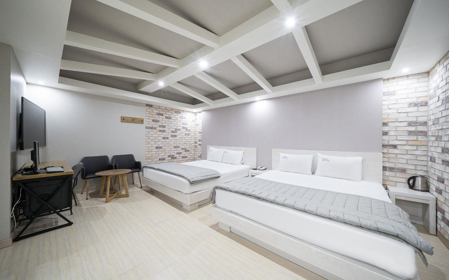 Habitación de hotel moderna con una cama grande, un escritorio con ordenador, una silla y una mesita.
