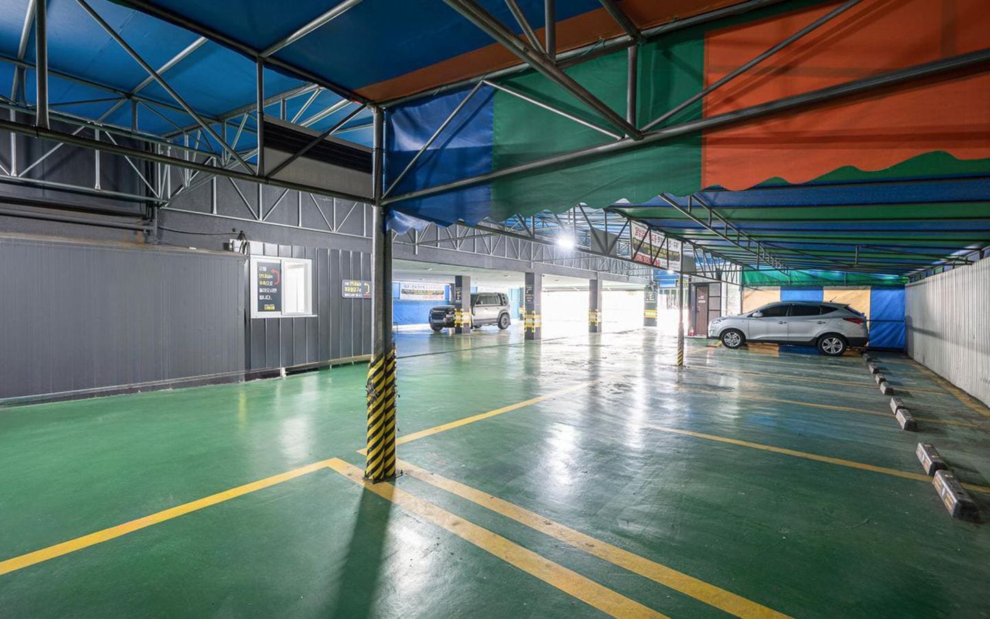 An indoor parking garage with multiple levels, marked parking spaces, and a clear ceiling structure.