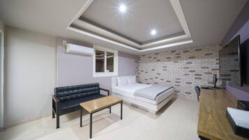 Un dormitorio moderno con cama, sofá, una mesita y televisor.