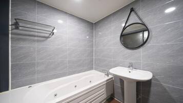 A modern bathroom with a bathtub, a sink, and a mirror.