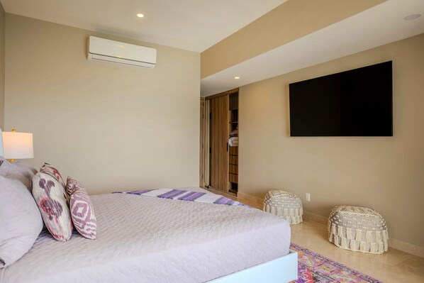 A bedroom with a bed, a TV mounted on the wall, and a wardrobe. - New Beachfront 4BD Deluxe Condo with 8 pools 4BD Condo for rent in North Hotel Z (Puerto Vallarta)