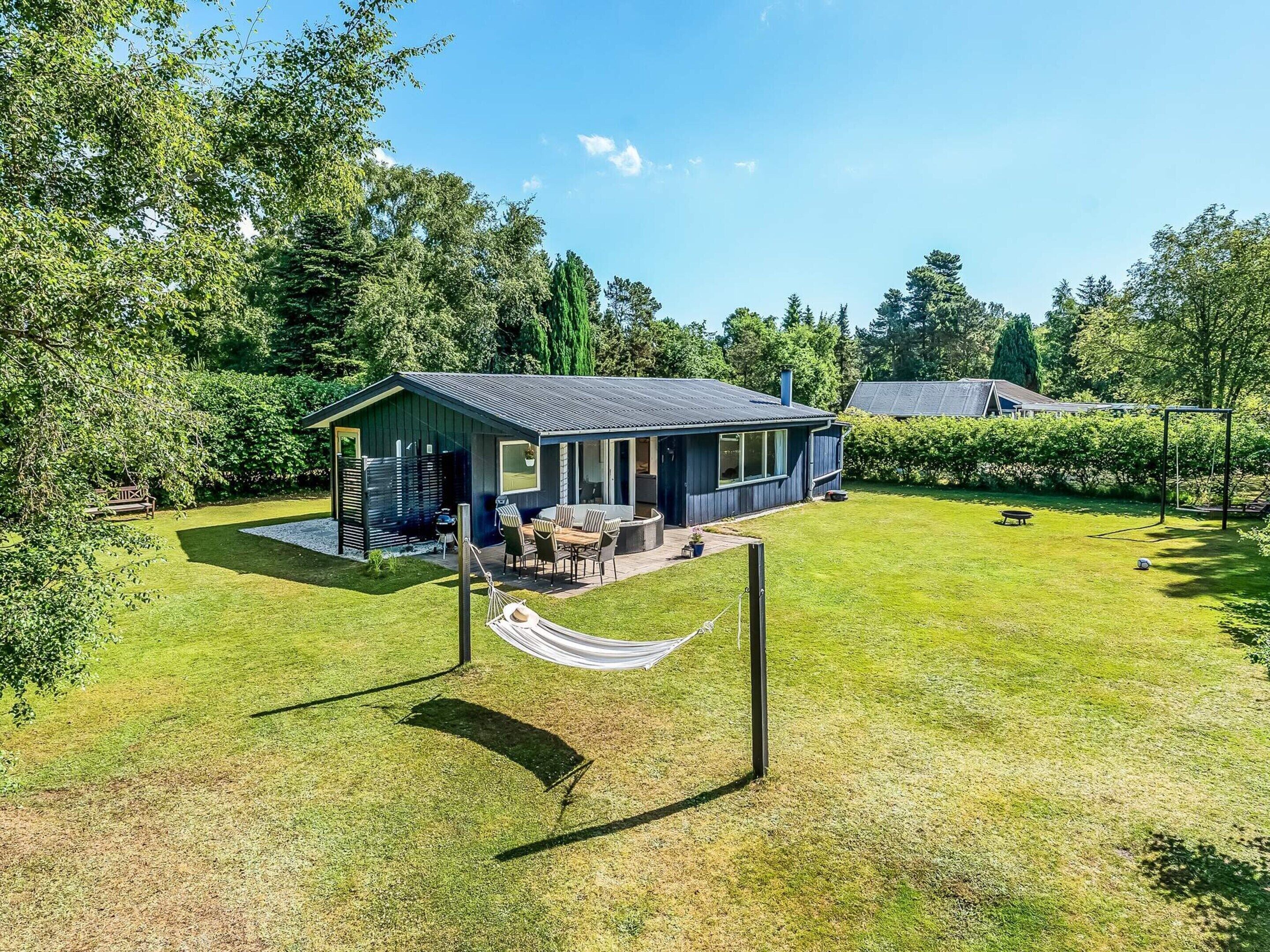 A modern house with a patio, a hammock, and a well-maintained lawn.
