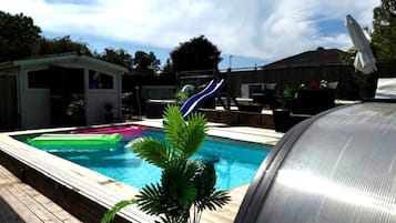 A backyard with a swimming pool, a barbecue grill, and a slide.