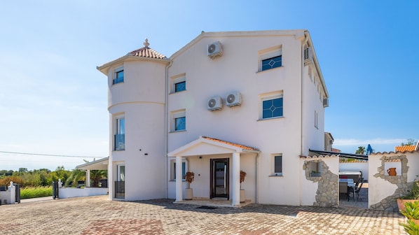A two-story building with a central entrance, multiple windows, and air conditioning units.