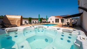 Une piscine avec des bains à remous, des chaises longues et des parasols.