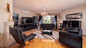 Un salon moderne avec un canapé noir, un fauteuil noir, une table basse et un téléviseur.
