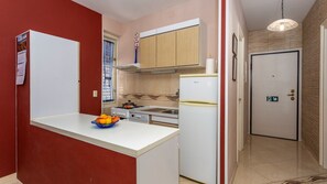 Cocina compacta con encimera blanca, estufa, lavaplatos y refrigerador.