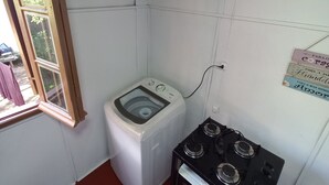 Une cuisine compacte équipée d’un lave-linge, d’une cuisinière à gaz et d’une petite fenêtre.