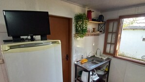 Une cuisine de taille réduite, équipée d’un réfrigérateur, d’un évier et d’une petite table.