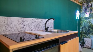 Une cuisine de taille réduite, dotée d’un plan de travail en bois, d’un robinet noir et d’un évier en acier inoxydable.