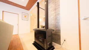 Ein modernes Wohnzimmer mit einem schwarzen Kaminofen, Holzböden und einer Wand mit Steinverkleidung.