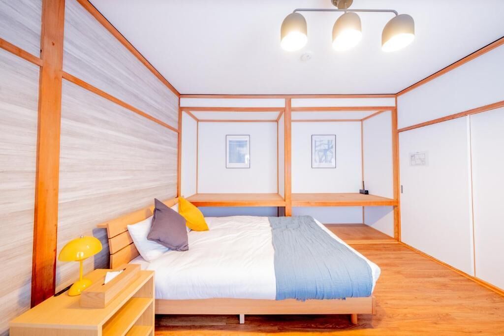 Un dormitorio con cama de madera, una mesita de noche con lámpara y un candelabro en el techo.