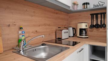 Et moderne køkken med stålvask, toaster, kaffemaskine og træskabe.