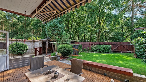 An outdoor patio with a table and chairs, surrounded by a stone wall and a wooden fence. - Holiday Home 'Ferienhaus Am Rander Der Lewitz' with Lake View, Wi-Fi and Air Conditioning (Lewitzrand)