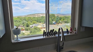 A kitchen with a large window, a sink, and a 'hello' decoration.