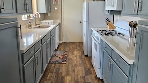 A kitchen with grey cabinets, a white refrigerator, a stove, and a microwave.