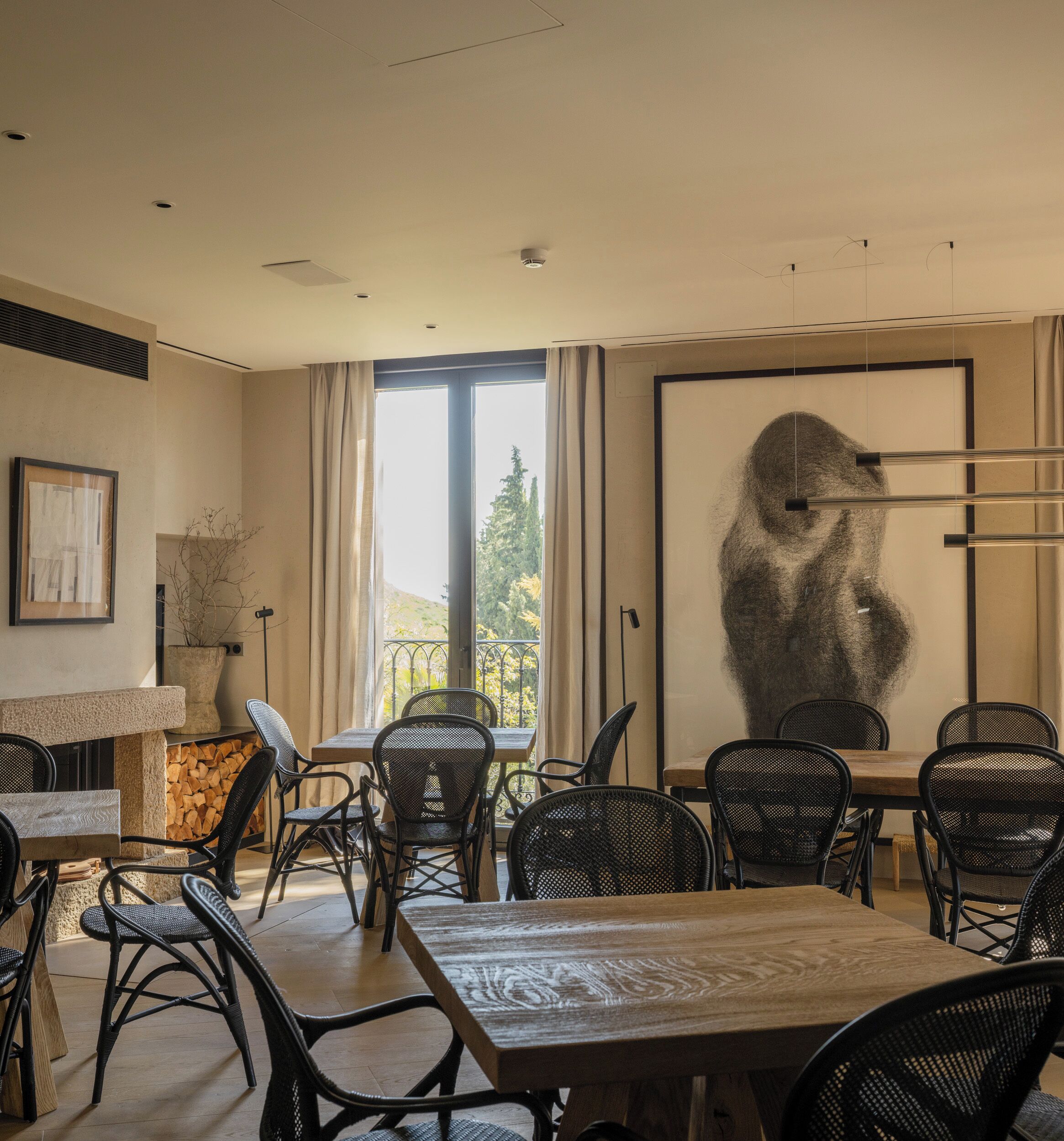 A modern dining area with a large window, wicker chairs, and a wooden table.