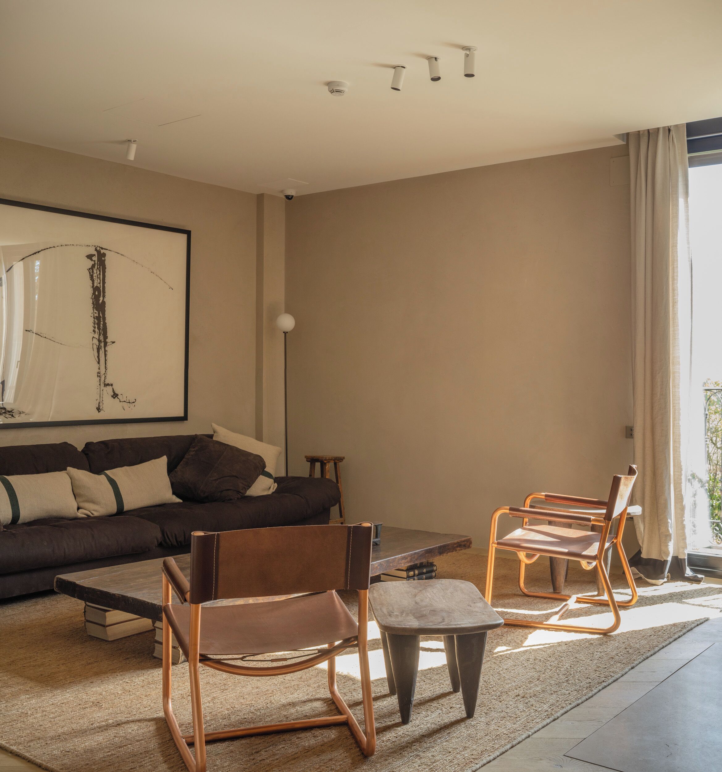 Ein modernes Wohnzimmer mit einer Couch, zwei Sesseln, einem Couchtisch und einer Stehlampe.