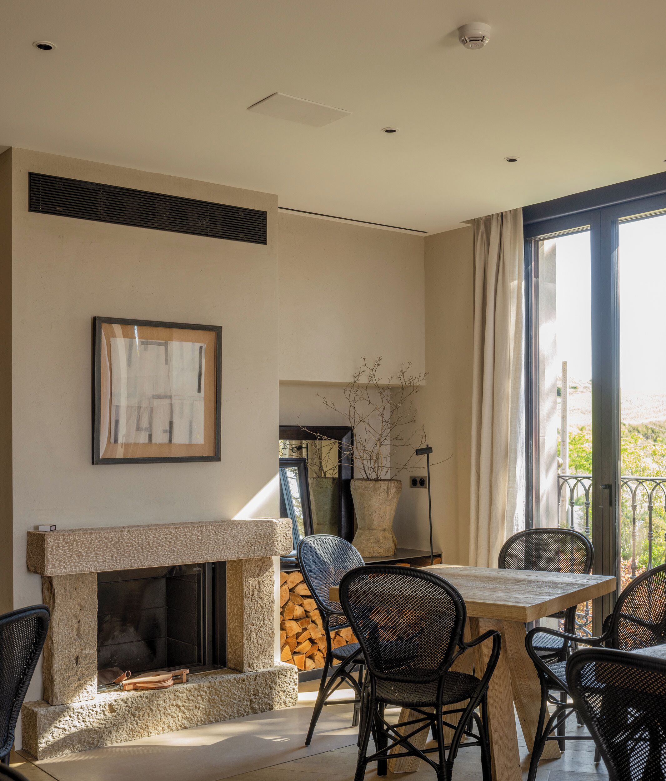 Una sala de estar moderna con chimenea, una mesa de comedor con sillas y un ventanal con cortinas.