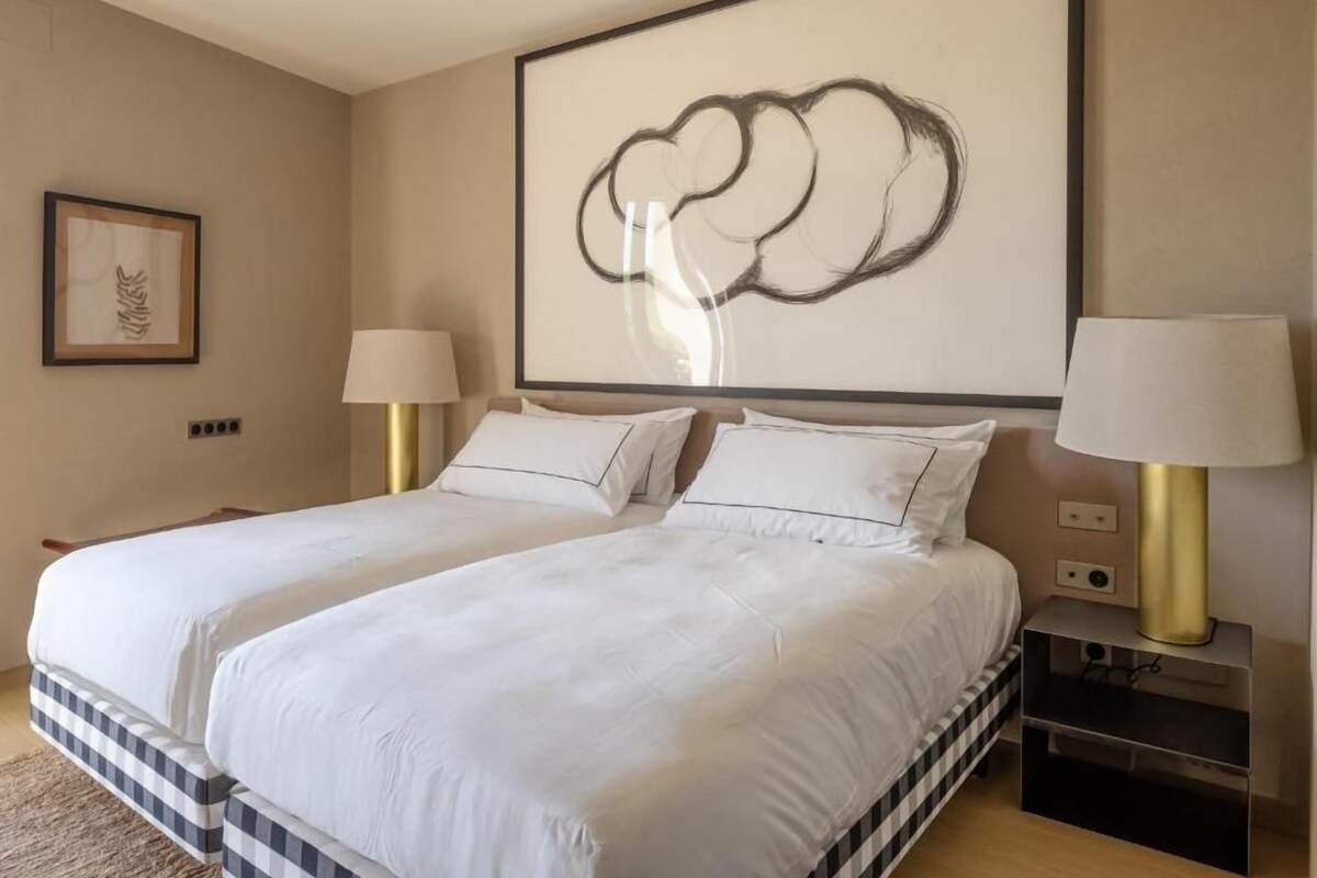 Une chambre d’hôtel avec un grand lit, deux tables de chevet, une œuvre d’art accrochée au mur et un tableau encadré.