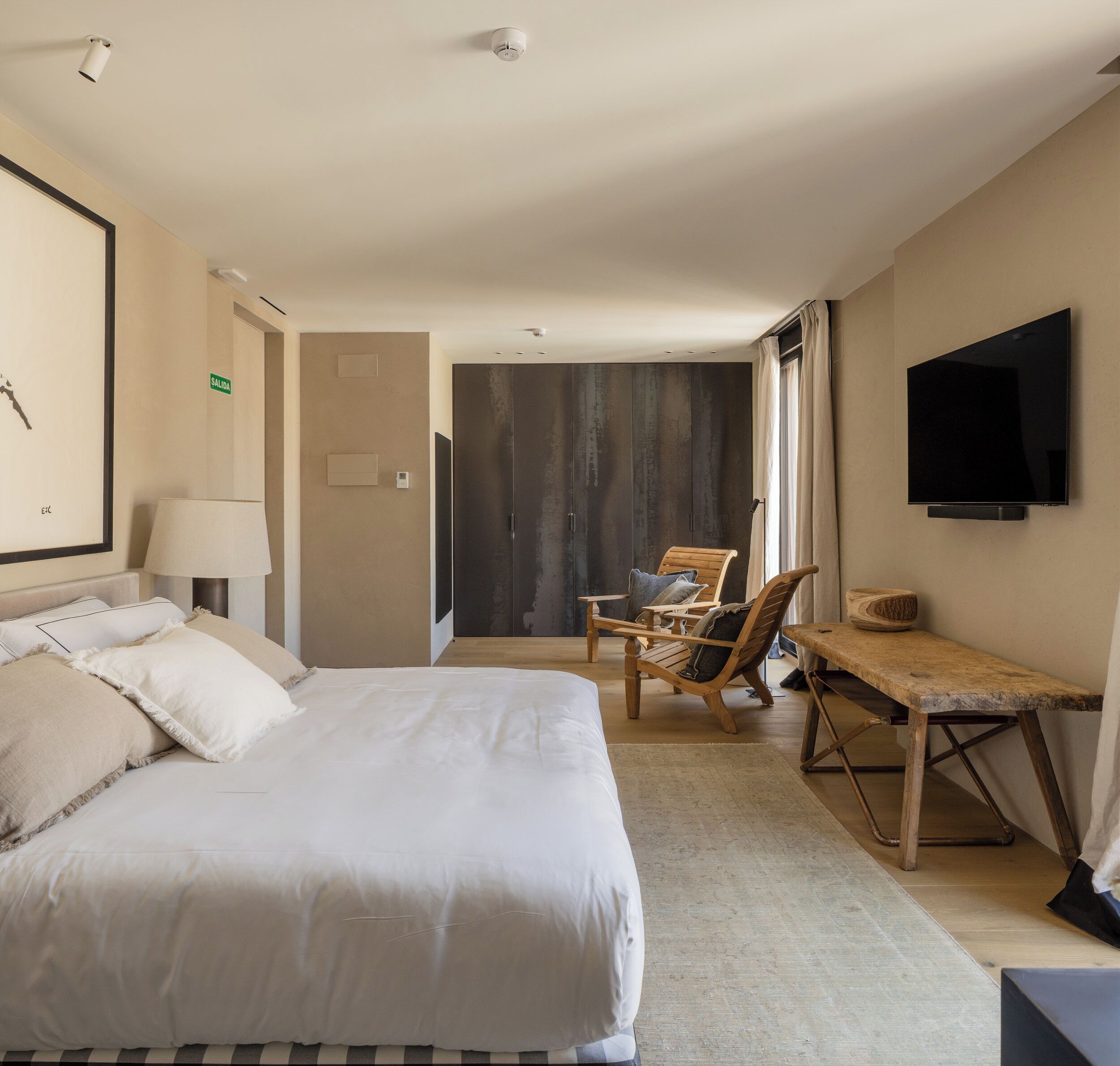 Una habitación de hotel con una cama grande, un escritorio, una silla, un televisor y un armario.