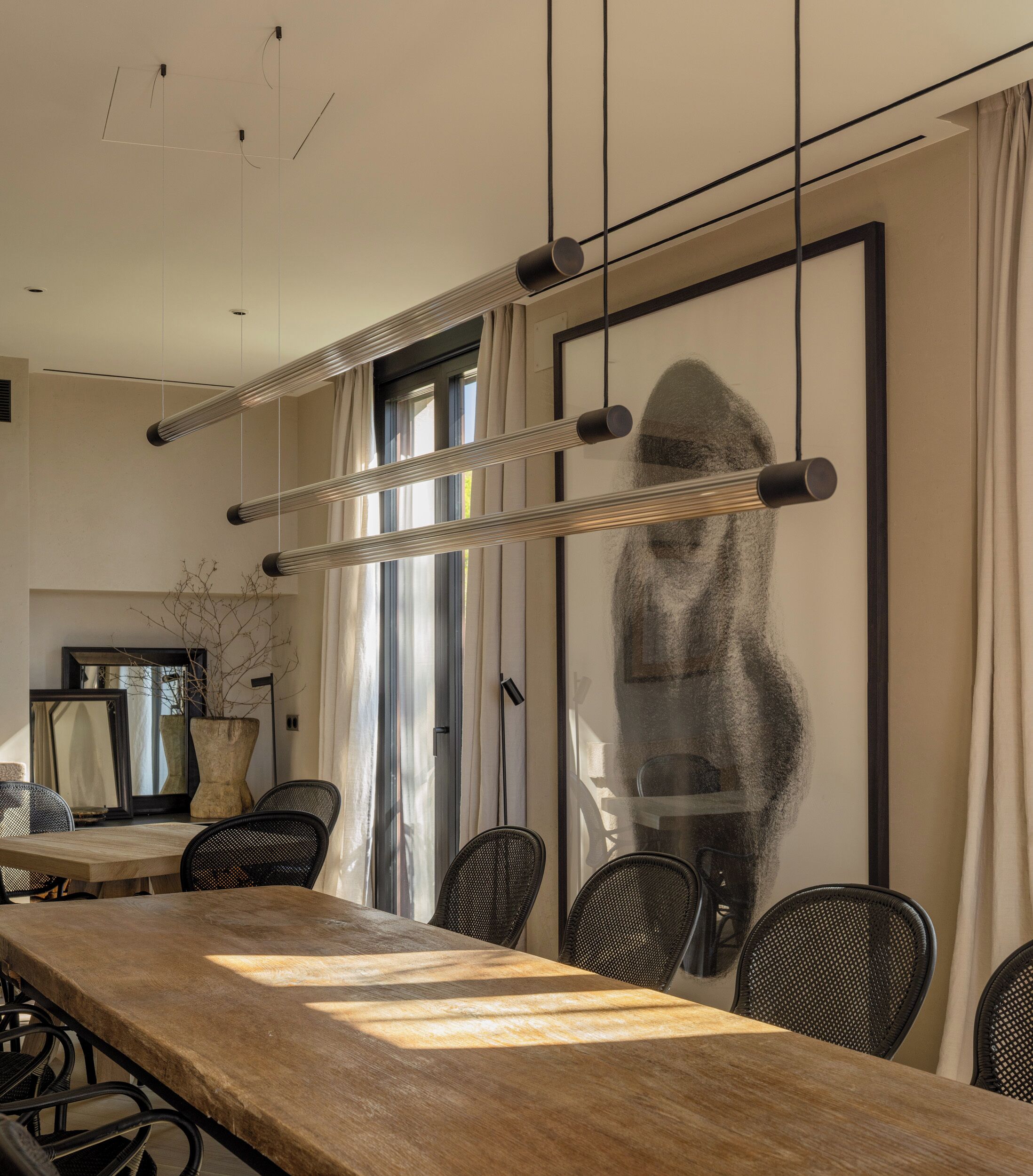 Un comedor moderno con una larga mesa de madera, sillas negras y una gran obra de arte enmarcada en la pared.