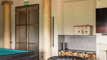 A billiards table, a leather armchair, a fireplace, and a door with a 'SALIDA' sign.