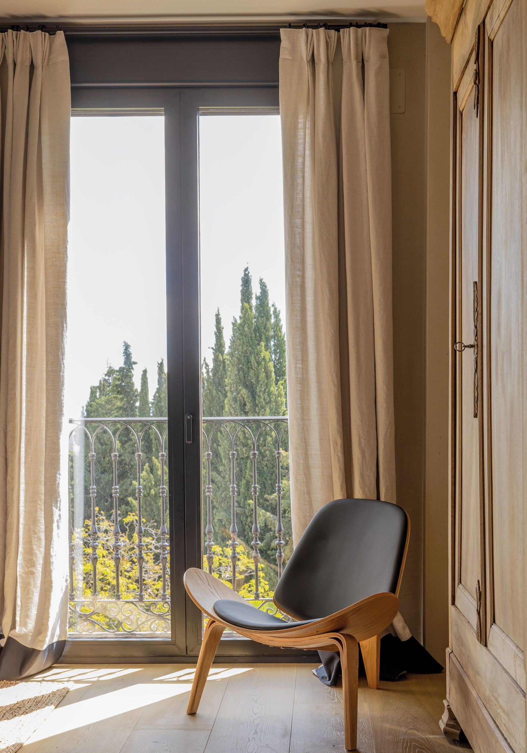A room with a sliding glass door leading to a balcony, a wooden chair, and a wardrobe.