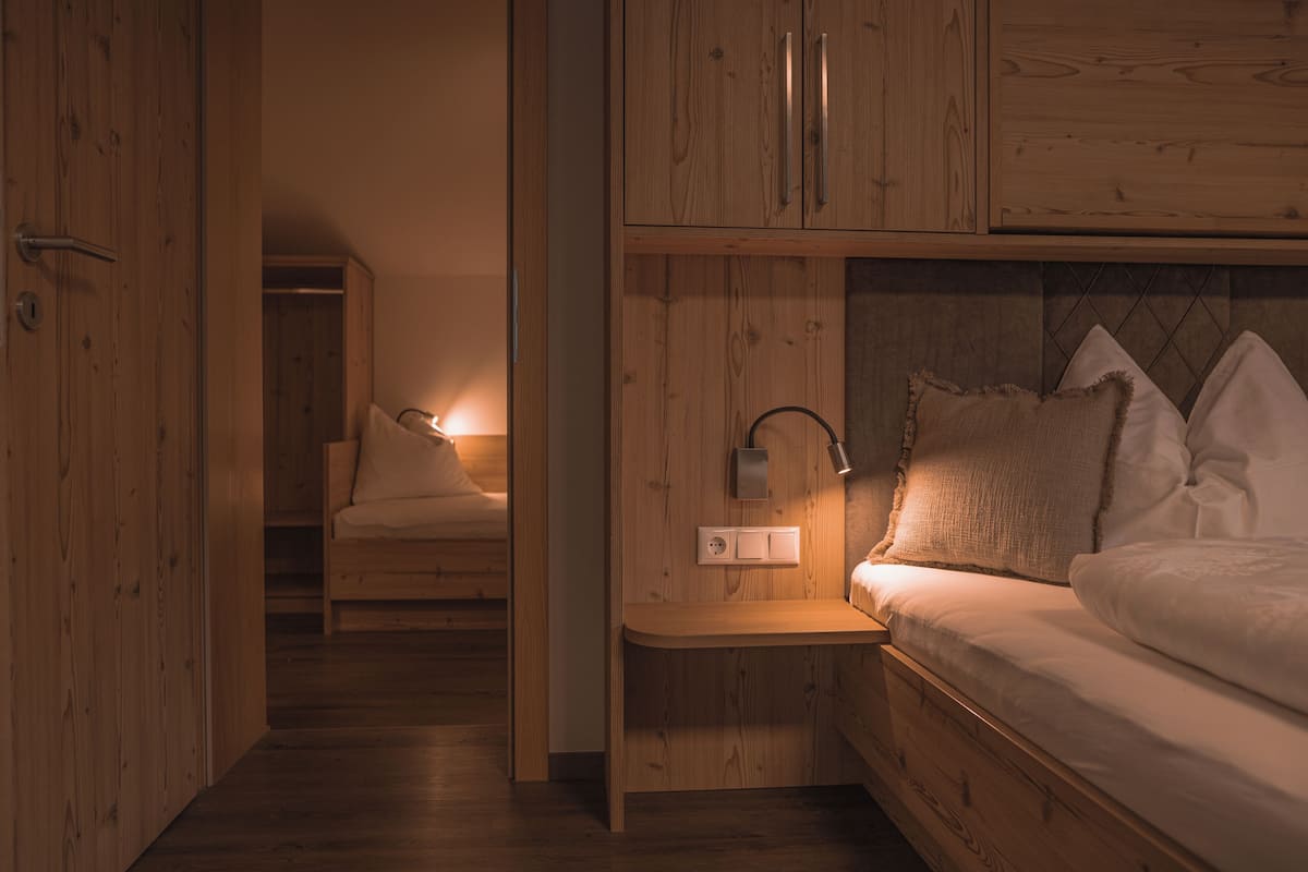 A bedroom with a wooden bed, bedside table, and a nightstand with a lamp.