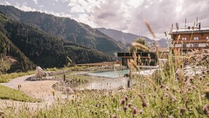 Eine Berglandschaft mit Schwimmbecken, einem Gebäude mit Schrägdach und blauem Himmel.