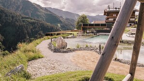 Ein Bergresort mit Schwimmbad, einer Holzterrasse und Blick auf den umliegenden Wald und die Berge.