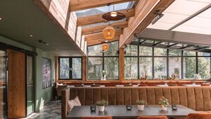 Ein Restaurant mit hohen Holzbalkendecken, großen Fenstern und einer langen Sitzbank.