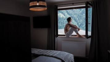 Una habitación con cama, ventana, radiador y lámpara colgante.