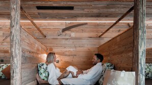Ein Holzblockhaus-Innenraum mit einem Bett, Kissen und einer Tasche auf dem Boden.
