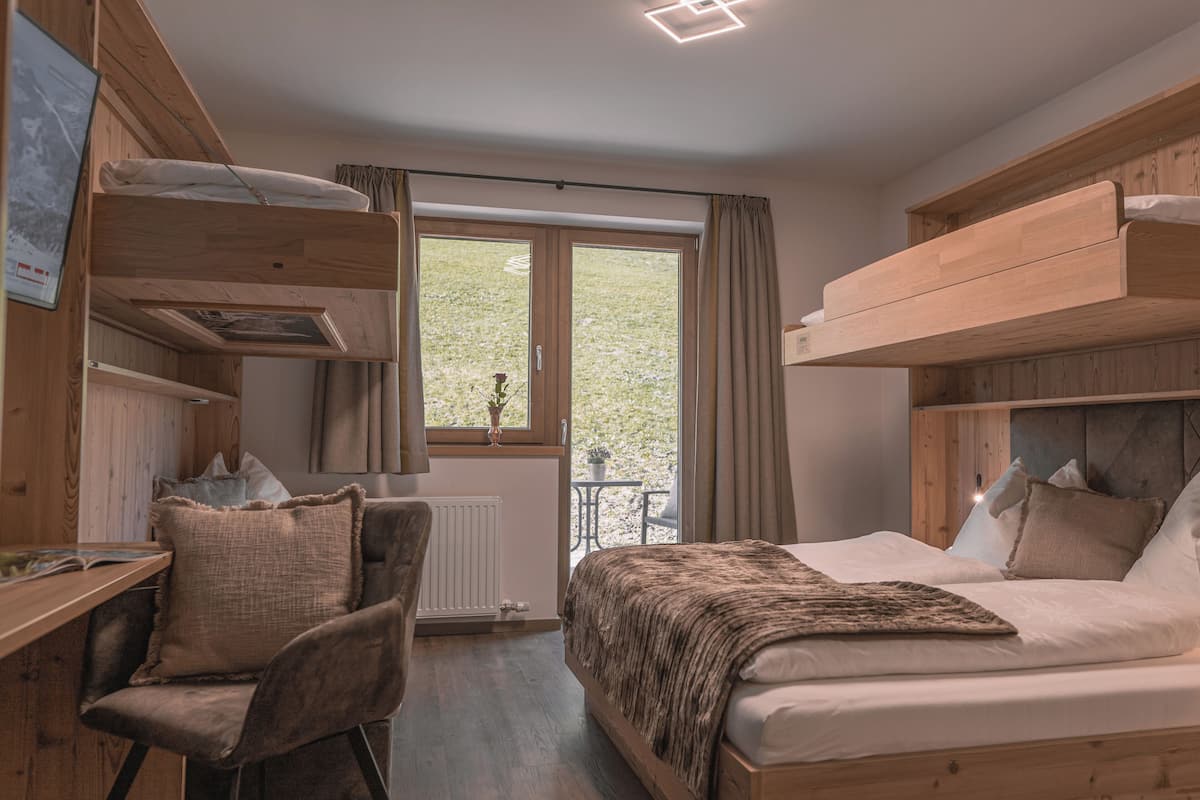 A room with a bunk bed, a desk, a chair, and a window with curtains.